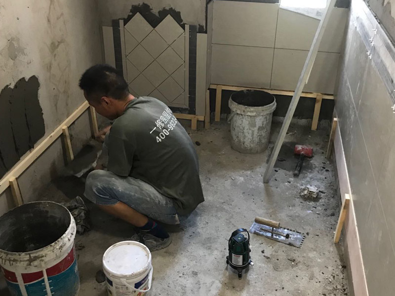 廁所瓷磚鋪貼裝修：首先應(yīng)除去基層表面的污垢，油漬，浮灰;除去基層上所有涂料層，膩?zhàn)訉?如果基層未能達(dá)到平整度要求，需對(duì)基層進(jìn)行預(yù)先的找平處理；鋪貼瓷磚前需事先找好垂直線，以此為基準(zhǔn)鋪貼的瓷磚高低均勻、垂直美觀;將調(diào)制好的漿料均勻地抹在瓷磚背面，要求漿料飽滿；將瓷磚平整地鋪貼在基層上，使用橡膠錘將瓷磚拍實(shí)鋪平。