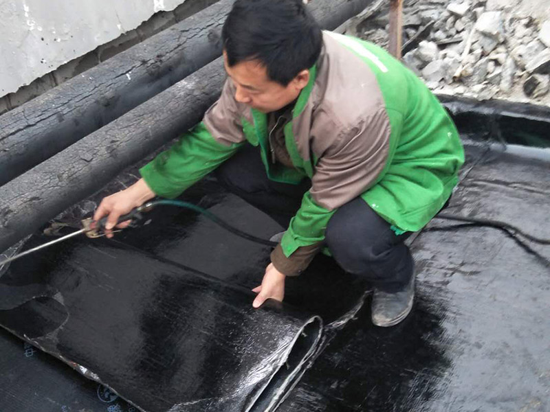 屋頂貼防水卷材：首先做好基礎(chǔ)準(zhǔn)備工作，清理基層，施工前將驗(yàn)收合格的基層表面塵土、建筑雜物清理干凈。接著涂刷基層處理劑，高聚物改性瀝青卷材施工，攪拌均勻后，用長把滾刷均勻涂刷于基層表面上，常溫經(jīng)過4h后，開始鋪貼卷材。熱熔封邊，將卷材搭接處用噴槍加熱，趁熱使二者粘結(jié)牢固，以邊緣擠出瀝青為度；末端收頭用密封膏嵌填嚴(yán)密。防水層蓄水試驗(yàn)，卷材防水層完工后，確認(rèn)做法符合設(shè)計(jì)要求，將所有雨水口堵住，然后灌水，水面應(yīng)高出屋面最高點(diǎn)20㎜，24h后進(jìn)行認(rèn)真觀察，尤其是管根、風(fēng)道根，不滲不漏為合格，否則應(yīng)進(jìn)行返工。