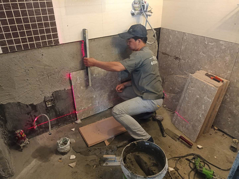 衛(wèi)生間貼磚施工：施工工藝流程; 基層處理--抹底子灰--彈線排磚--侵磚--鑲貼--擦縫--交工驗收 用一比三的水泥砂漿打底,打底厚度5~~7mm，待底子灰干六七成干時候，按圖紙要求，進行彈線，排磚。立好皮數(shù)桿，排磚形式有主要兩種直縫和錯縫。當?shù)孛嬗蟹核臅r候，注意安排好泛水。侵泡瓷磚，時間不少于兩個小時，陰干通常是3~~5小時。瓷磚在鑲貼時候，瓷磚下口坐在八字尺或直尺上。鋪貼的方式有離縫和無縫。鑲貼瓷磚從陽角開始，自下向上貼，瓷磚背面刀灰，貼上用力壓，用鏟刀木柄輕輕敲打，鋪貼時候砂漿飽滿，缺灰重貼，不得塞灰，貼6~~8塊，用靠尺校正。水管處先鋪周圍整塊磚，后鋪異型磚。最后擦縫。