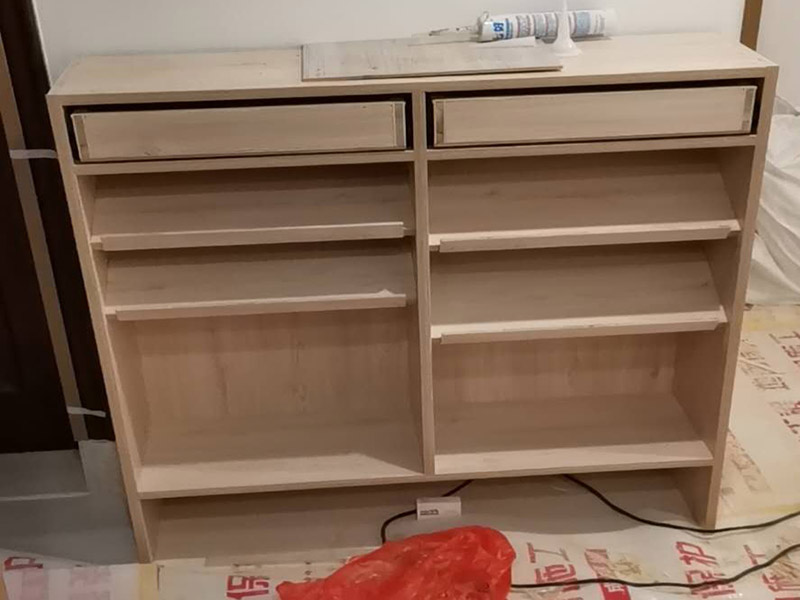 家具柜體安裝：用墊布點(diǎn)好地板，先從靠墻的一端寬du側(cè)板開(kāi)始組裝，將寬側(cè)板平放于地面上(離后墻面保持700mm間隔)。首先將填好的三合一膠塞的板件，平放在墊布上，檢查孔距與圖紙相符，并裝上三合一單連桿。然后將固層釘上木塞，固定于寬側(cè)板上面，頂板大柄孔朝上，其余固層都朝下，腳線大柄孔朝內(nèi)(中間固層與L架高度一致，即底板到固層內(nèi)空為960mm，現(xiàn)場(chǎng)打?qū)影蹇?。放上側(cè)板，釘上木塞，木塞要求連通兩邊的固層。在第二個(gè)柜固層上面裝好雙連桿，留意雙連桿上面大柄只能鎖住一半，即90°。當(dāng)兩件固層與側(cè)板固定后再同時(shí)擰緊大柄。 釘背板：把裝好的整體柜側(cè)放在點(diǎn)好墊布的地板上面，墊平側(cè)板成統(tǒng)一平面。用拉尺量好柜子的對(duì)角尺寸，調(diào)至相等，從寬測(cè)板處開(kāi)始裝第一塊背板，留意假如中間有固層釘釘子時(shí)，先用鉛筆畫(huà)好固層的中央線，再釘釘子。