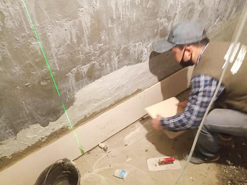 衛(wèi)生間墻面貼磚：施工前將需要的材料整齊堆放在一旁待用。首先應除去基層表面的污垢，油漬，浮灰;除去基層上所有涂料層，膩子層;如果基層未能達到平整度要求，需對基層進行預先的找平處理。 鋪貼瓷磚前需事先找好垂直線，以此為基準鋪貼的瓷磚高低均勻、垂直美觀;此外，施工前在墻體四周需彈出標高控制線，在地面彈出十字線，以控制地磚分隔尺寸。 加水后將粘結劑漿料攪拌至潤滑均勻，無明顯塊狀或糊狀結塊，攪拌后的漿料靜置5-10分鐘后再稍加攪拌1-2分鐘即可使用。在開始鋪貼施工前，需要先清理瓷磚表面的浮灰，污垢等。將調制好的漿料均勻地抹在瓷磚背面，要求漿料飽滿。將瓷磚平整地鋪貼在基層上，使用橡膠錘將瓷磚拍實鋪平。施工過程中，可小幅度轉動瓷磚，使?jié){料與瓷磚背面充分接觸。