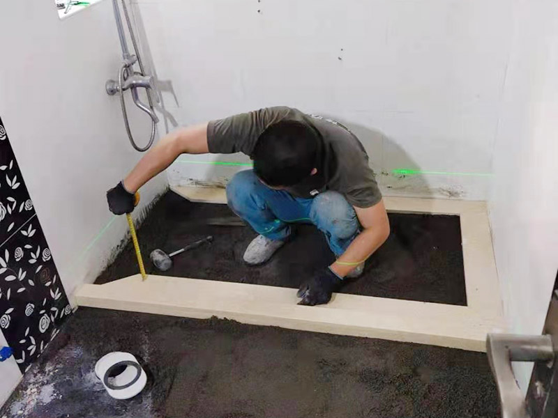 衛(wèi)生間貼磚施工：應全部清理墻面上的各類污物，打掃干凈現(xiàn)場，特別是腳落里。用泥刀先批墻，后用水泥漿找平。這個工序很重要，確保底子平，防止貼后空鼓。墻面要刷防水涂料，防止貼后浸水，一般高度不低于1.8米，刷的時候會稍高一些。根據(jù)設(shè)計鋪貼圖樣的要求，確定排磚方案，用墨斗彈線，以減少施工損耗。用鋸齒鏝刀拉槽這點是目前新工藝區(qū)別老工藝的一點，使用將粘結(jié)劑漿料抹在待鋪貼基層表面，經(jīng)由鋸齒鏝刀梳理后的條狀漿料飽滿并連續(xù)不間斷。瓷磚上墻將經(jīng)過預先清潔的瓷磚平整地鋪貼在粘結(jié)劑漿料基層上，使用橡膠錘將瓷磚拍實鋪平。施工過程中，可小幅度轉(zhuǎn)動瓷磚，使?jié){料與瓷磚背面充分接觸。專家建議在鋪貼時，隨機取下已鋪貼于基層上的瓷磚作檢查。確保漿料與瓷磚背面的充分接觸。